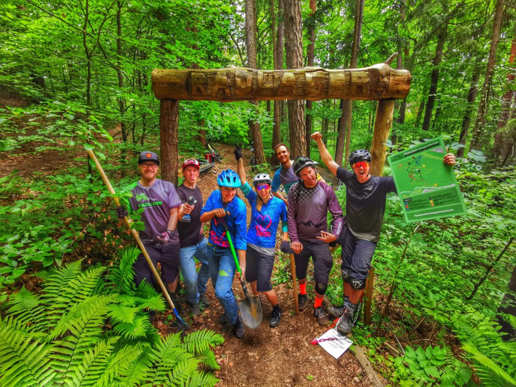 Gruppe am Torbogen mit der Aufschrift Radlager – dem Einstieg zum Enzi Trail